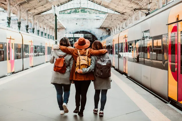 friends at train station wearing backpacks 
